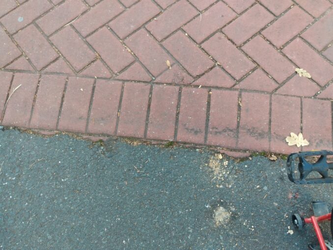Edge of the fake block paving, showing small amounts of red material that have escaped the edge of the mould
