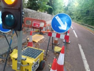 Temporary traffic light, cones, and a yellow ramp giving access to the carriageway from the pavement.